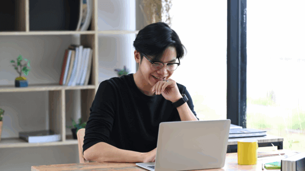 A male learner with glasses and short brown hair looking at his laptop